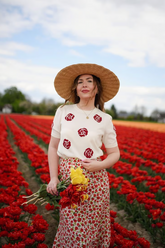 a lady in a red rose jacquard top and a floral skirt